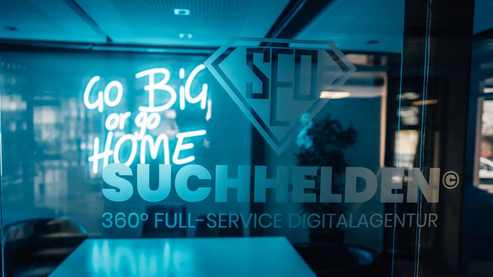 Beleuchteter Suchhelden-Schriftzug âGo big or go homeâ an der Glaswand in OsnabrĂŒck