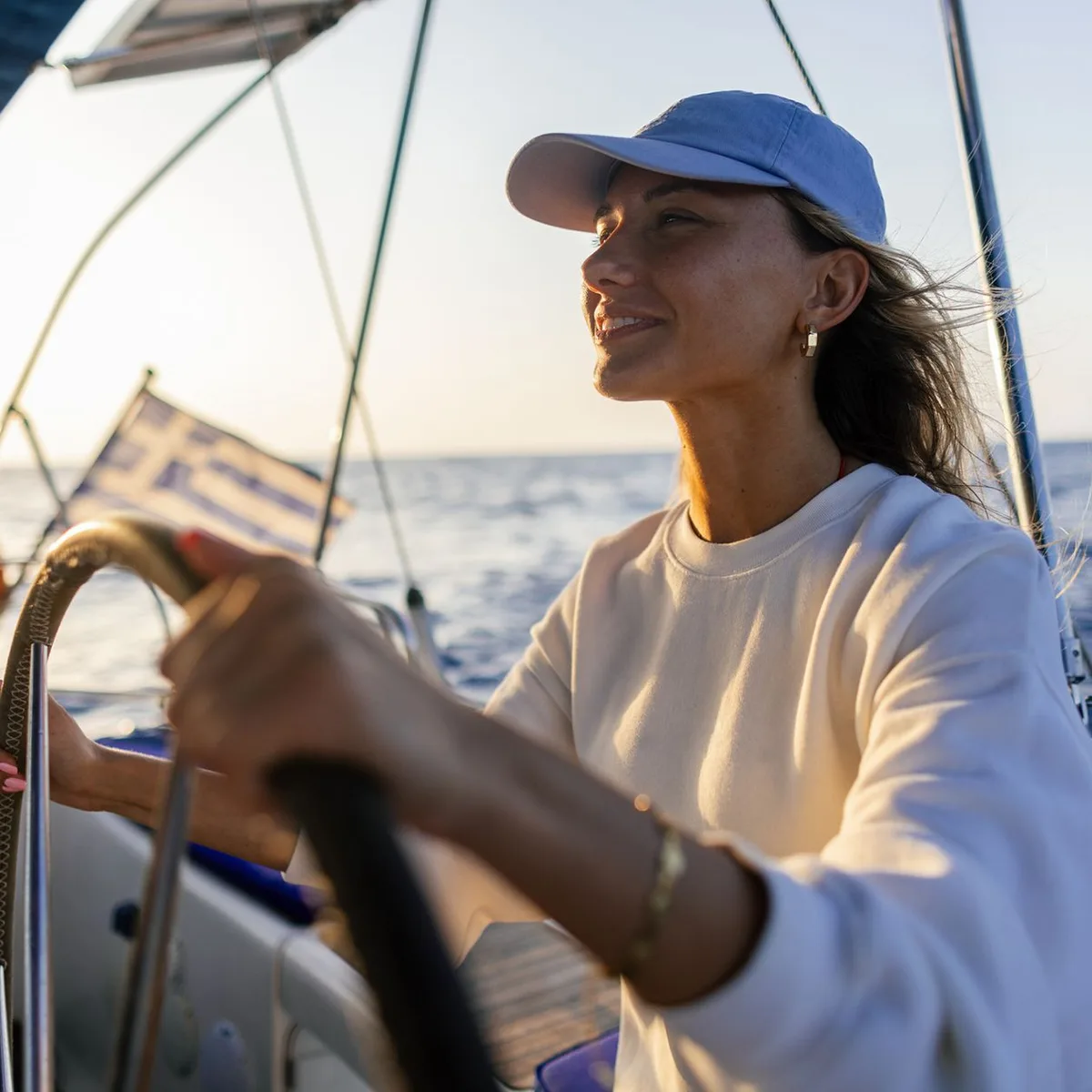 Frau in weißem Jackett am Steuerrad eines Segelbootes von 1ayachtcharter