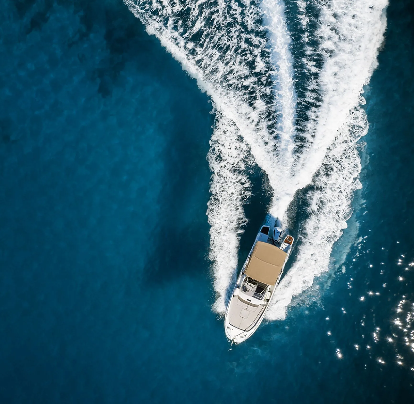 Motorboot von 1ayachtcharter von oben auf dunklem Wasser mit Kielwasser